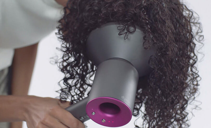 Gros plan de face du Styler Dyson Airwrap™ enroulant une mèche de cheveux.