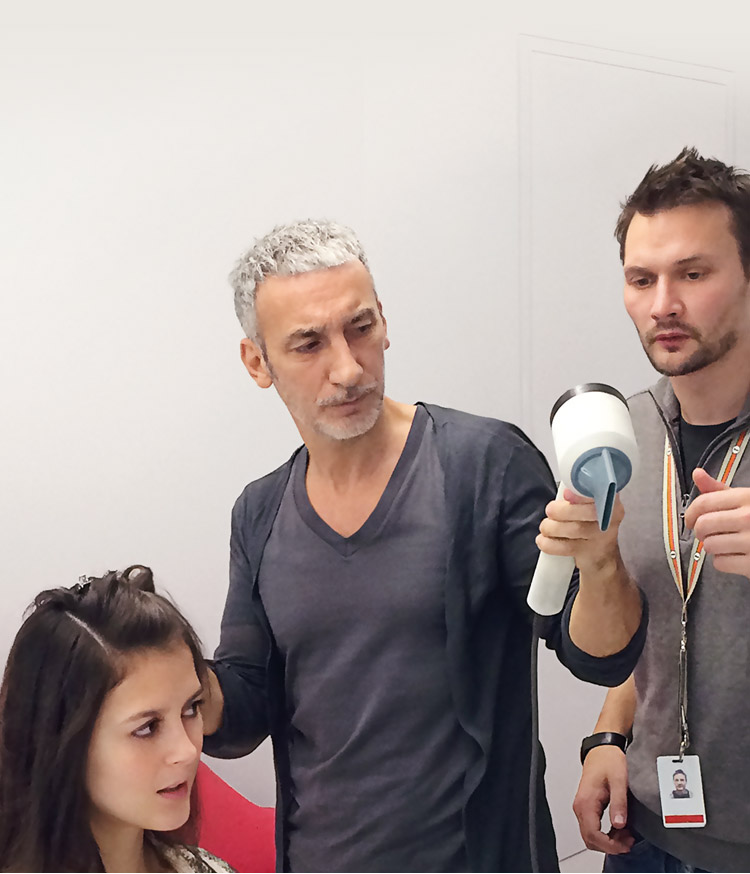 A hair stylist using the Dyson Supersonic&trade; hair dryer, accompanied by two Dyson engineers